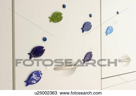 Close-up of blue fish magnets on white cupboard doors View Large Photo Image Stock Image - Close-up of blue fish magnets on white cupboard doors. Fotosearch