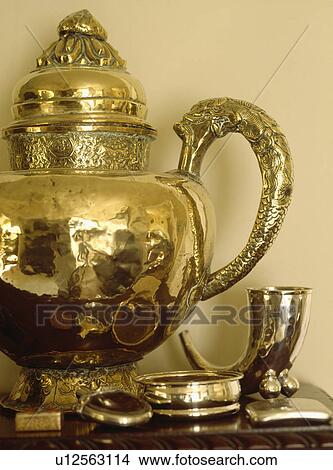 Picture - Close-up of brass Moroccan jug on table with brass bangles and boxes. Fotosearch