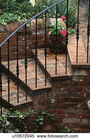 Stock Photography - Close up of brick steps and black cast iron railings in town garden. Fotosearch