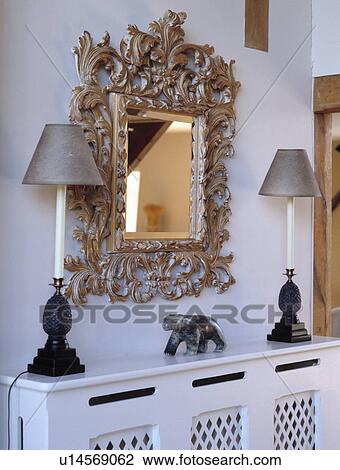 Close-up of carved wooden mirror and lamps above radiator cover View Large Photo Image Stock Image - Close-up of carved wooden mirror and lamps above radiator cover. Fotosearch
