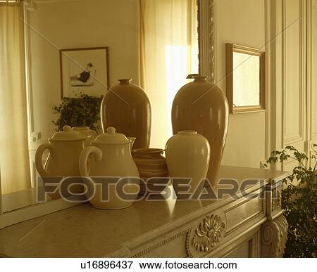 Stock Photo - Close-up of collection of cream vases in front of mirror above mantelpiece. Fotosearch
