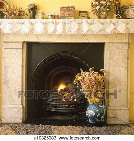 Close-up of dried flowers in jug in front of lighted fire in marble fireplace with lace trimming on mantelpiece View Large Photo Image Stock Image - Close-up of dried flowers in jug in front of lighted fire in marble fireplace with lace trimming on mantelpiece. Fotosearch
