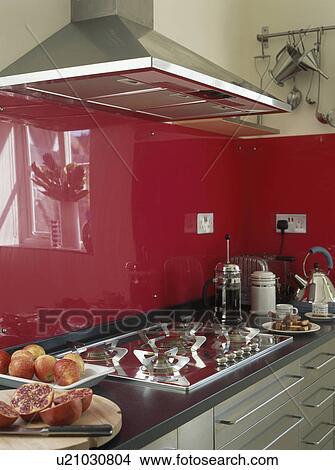 Close-up of gas hob below stainless steel extractor fan in modern kitchen with red glass panels View Large Photo Image Picture - Close-up of gas hob below stainless steel extractor fan in modern kitchen with red glass panels. Fotosearch