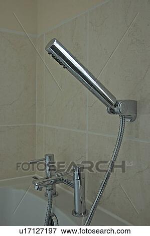 Close-up of modern cylindrical chrome shower head and tap above bath View Large Photo Image Stock Photo - Close-up of modern cylindrical chrome shower head and tap above bath. Fotosearch