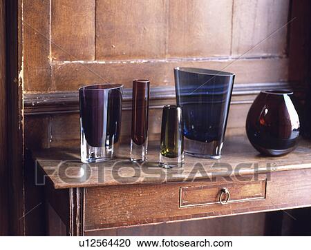 Stock Image - Close-up of nineties LSA dark glass vases on antique table. Fotosearch