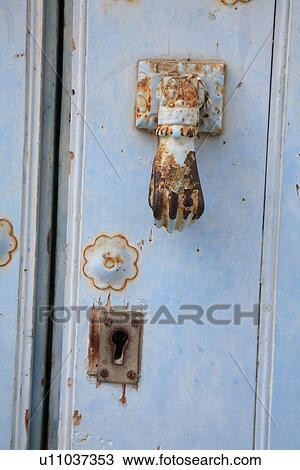 Stock Image - Close up of old hand shaped door knocker. Fotosearch