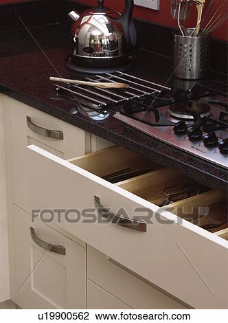 Stock Image - Close-up of open cutlery drawer below kitchen hob. Fotosearch