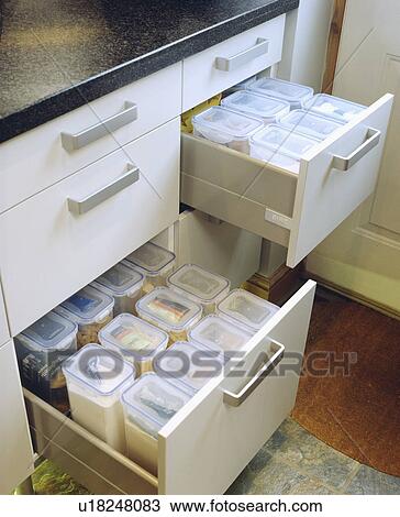 Stock Image - Close-up of open kitchen drawers with large plastic storage boxes . Fotosearch