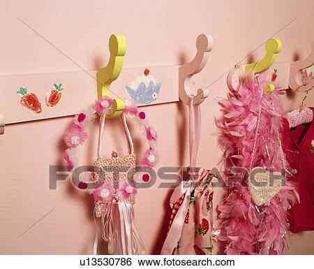 Stock Photograph - Close-up of painted hooks with girl's pink bags and feathered boas. Fotosearch