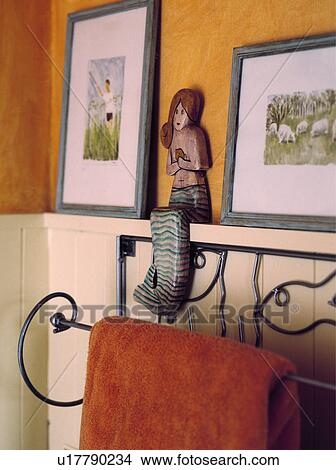 Close-up of pictures and wooden mermaid ornament above wrought iron towel rail View Large Photo Image Picture - Close-up of pictures and wooden mermaid ornament above wrought iron towel rail. Fotosearch