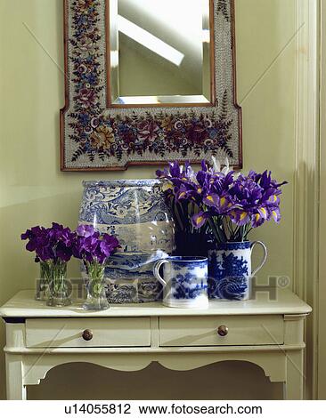 Close-up of purple pansies in glass vases and blue irises in blue+white jug on cream console table below floral mirror View Large Photo Image Stock Image - Close-up of purple pansies in glass vases and blue irises in blue+white jug on cream console table below floral mirror. Fotosearch
