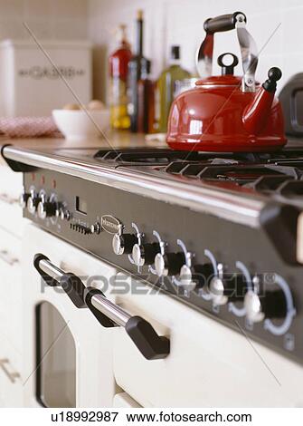 Stock Photo - Close-up of red kettle on stainless steel oven hob. Fotosearch