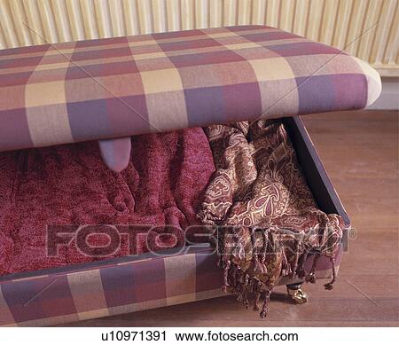 Stock Image - Close-up of red shawls in purple checked ottoman chest. Fotosearch