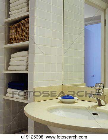 Stock Photo - Close-up of shelves with towels and circular basin with single chrome tap. Fotosearch