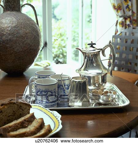 Close-up of silver coffeepot and jug with blue+white cups on silver tray beside metal vase on table View Large Photo Image Stock Photograph - Close-up of silver coffeepot and jug with blue+white cups on silver tray beside metal vase on table. Fotosearch