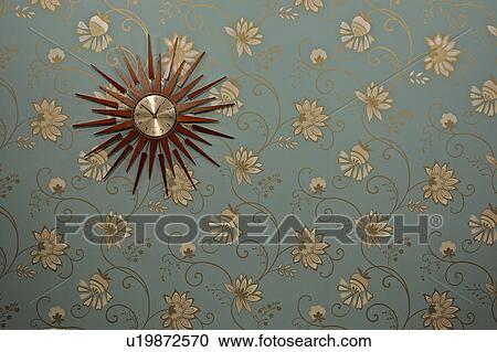Close-up of sunburst clock on modern blue wallpaper with gold and cream stylised flower pattern View Large Photo Image Stock Image - Close-up of sunburst clock on modern blue wallpaper with gold and cream stylised flower pattern. Fotosearch