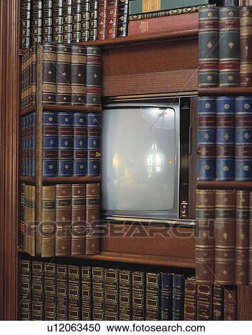 Stock Image - Close-up of television concealed by folding door disguised as bookcase. Fotosearch