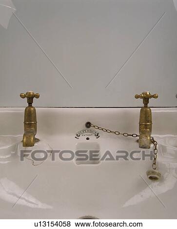 Stock Photo - close-up of white bathroom basin with brass taps. Fotosearch