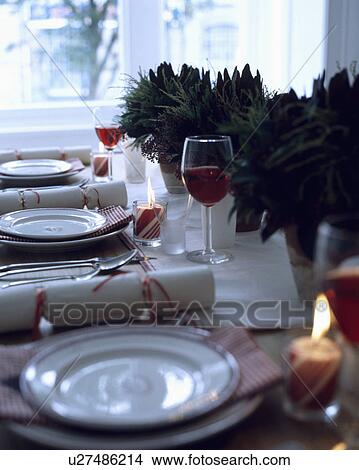 Close-up of white plates and Christmas crackers on table decorated simply with green leaves in vases View Large Photo Image Picture - Close-up of white plates and Christmas crackers on table decorated simply with green leaves in vases. Fotosearch