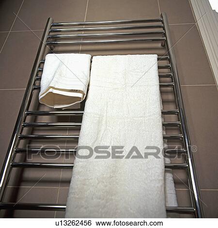 Stock Photograph - Close up of white towels on chrome wall mounted towel rail in modern bathroom. Fotosearch