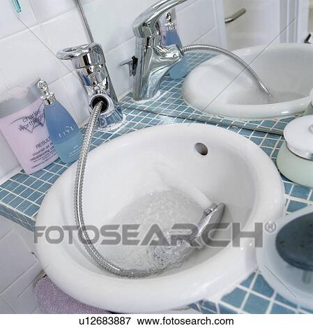 Stock Photo - Closeup of white hand basin with shower attachment. Fotosearch