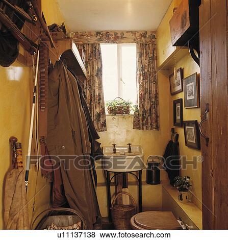 Coats on rack beside small old basin in yellow cloakroom with fishing equipment View Large Photo Image Stock Photo - Coats on rack beside small old basin in yellow cloakroom with fishing equipment. Fotosearch