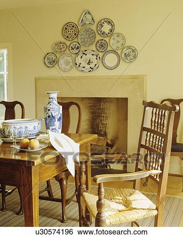 Collection of blue+white plates in triangular formation above fireplace in dining room with antique rush-seated chair View Large Photo Image Stock Photograph - Collection of blue+white plates in triangular formation above fireplace in dining room with antique rush-seated chair. Fotosearch