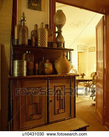 Collection of large rattan bottles on bamboo cupboard in hall beside open door to dining room View Large Photo Image Stock Image - Collection of large rattan bottles on bamboo cupboard in hall beside open door to dining room. Fotosearch