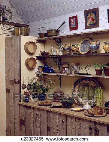 Collection of pottery jugs and plates on wooden shelves above rustic wooden fitted kitchen cupboards View Large Photo Image Stock Photography - Collection of pottery jugs and plates on wooden shelves above rustic wooden fitted kitchen cupboards. Fotosearch