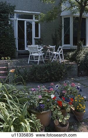 Stock Photography - Colourful annuals in pots on patio in front of townhouse. Fotosearch