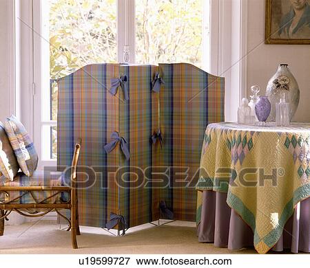 Stock Photo - Colourful checked screen and yellow patchwork tablecloth in living room. Fotosearch