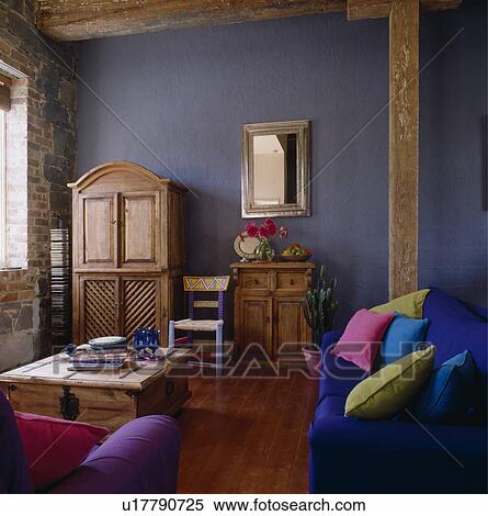 Colourful cushions on blue sofa in modern blue living room with old pine cupboard View Large Photo Image Stock Photography - Colourful cushions on blue sofa in modern blue living room with old pine cupboard. Fotosearch