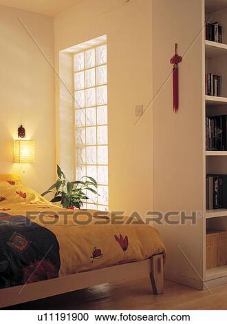 Colourful duvet on bed beside glass brick internal window in economy-style basement bedroom View Large Photo Image Stock Image - Colourful duvet on bed beside glass brick internal window in economy-style basement bedroom. Fotosearch