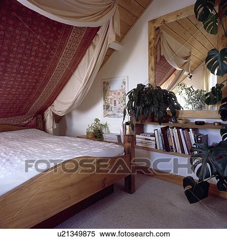 Cream Drapes And Indian Cotton Fabric On Sloping Ceiling Above Pine Bed In Attic Bedroom Stock Photography
