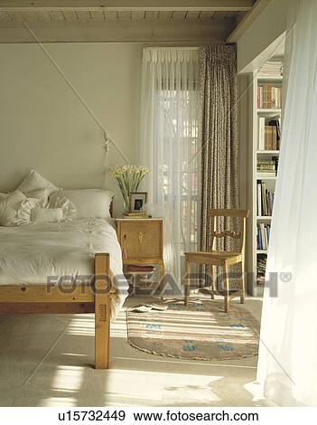 Cream linen on pine bed in bedroom with sheer white curtains at windows View Large Photo Image Stock Photo - Cream linen on pine bed in bedroom with sheer white curtains at windows. Fotosearch