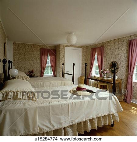 Cream pillows and bedcovers on twin beds in bedroom with neutral wallpaper and pink curtains View Large Photo Image Picture - Cream pillows and bedcovers on twin beds in bedroom with neutral wallpaper and pink curtains. Fotosearch