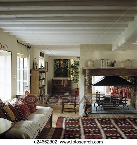 Cream sofa and open central fireplace in traditional cottage living room View Large Photo Image Stock Image - Cream sofa and open central fireplace in traditional cottage living room. Fotosearch