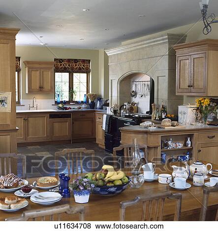 Crockery on table in large kitchen with fitted pine units View Large Photo Image Stock Photo - Crockery on table in large kitchen with fitted pine units. Fotosearch