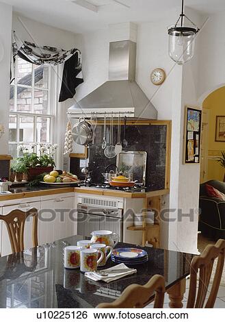 Cups on black marble-topped table in kitchen with stainless steel extractor fan above oven View Large Photo Image Stock Photograph - Cups on black marble-topped table in kitchen with stainless steel extractor fan above oven. Fotosearch