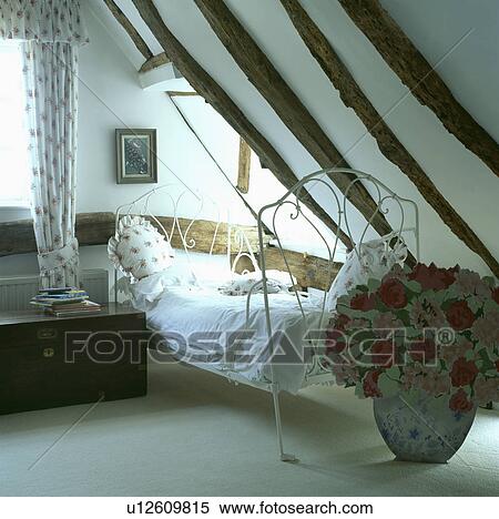 Cut-out floral screen in front of white iron antique bed in beamed attic bedroom with white carpet and wooden chest View Large Photo Image Stock Photography - Cut-out floral screen in front of white iron antique bed in beamed attic bedroom with white carpet and wooden chest. Fotosearch