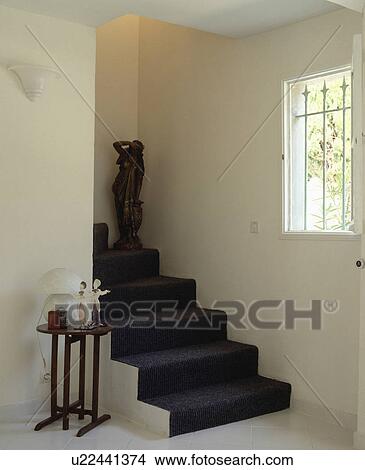 Dark grey carpet on stairs in white hall with ceramic figures on small table View Large Photo Image Picture - Dark grey carpet on stairs in white hall with ceramic figures on small table. Fotosearch