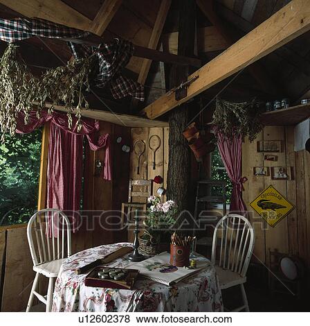 Stock Photo - Dining table and chairs in wooden treehouse with large crossbeam. Fotosearch