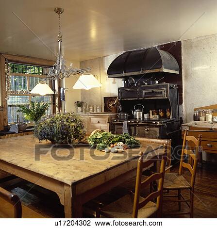 Double pendant light above large pine table with ladderback chairs in kitchen with extractor above black range oven View Large Photo Image Stock Image - Double pendant light above large pine table with ladderback chairs in kitchen with extractor above black range oven. Fotosearch