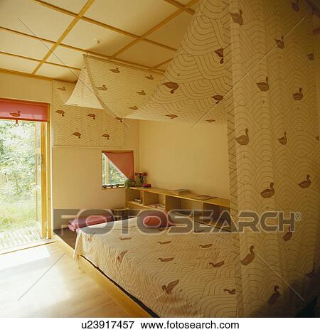 Duck-patterned cotton canopy over bed with matching bedcover in child's bedroom with grid-pattern ceiling View Large Photo Image Stock Photo - Duck-patterned cotton canopy over bed with matching bedcover in child's bedroom with grid-pattern ceiling. Fotosearch
