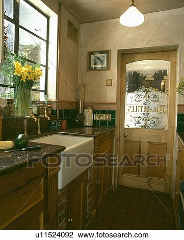 Stock Image - Engraved glass panel in door of kitchen with white ceramic sink . Fotosearch