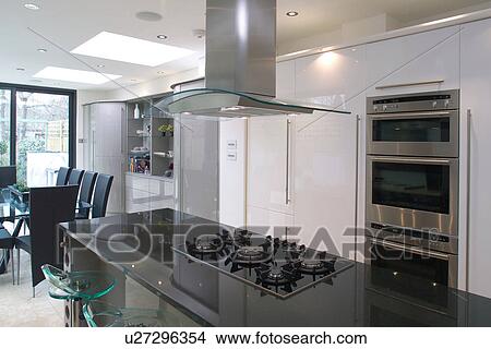 Extractor above hob set into island unit with granite worktop in modern white openplan kitchen and dining room View Large Photo Image Picture - Extractor above hob set into island unit with granite worktop in modern white openplan kitchen and dining room. Fotosearch