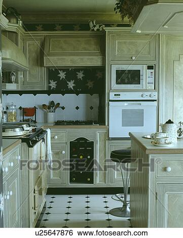 Fitted eye-level oven and microwave in kitchen with marble-effect fitted cupboards and white+black flooring View Large Photo Image Stock Photograph - Fitted eye-level oven and microwave in kitchen with marble-effect fitted cupboards and white+black flooring. Fotosearch