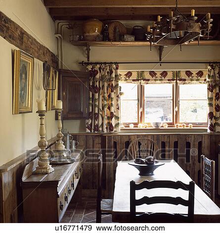 Floral curtains at small window in cottage dining room with wooden table and chairs and sideboard View Large Photo Image Stock Photo - Floral curtains at small window in cottage dining room with wooden table and chairs and sideboard. Fotosearch