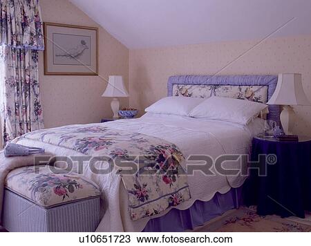 Floral-patterned upholstered headboard on bed with matching quilt and white linen with cushions on ottoman at the foot of the bed View Large Photo Image Stock Image - Floral-patterned upholstered headboard on bed with matching quilt and white linen with cushions on ottoman at the foot of the bed. Fotosearch