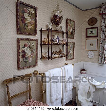 Floral pictures on either side of 3-tier Victorian wall shelf in traditional bathroom with towels on brass towel rail View Large Photo Image Stock Photo - Floral pictures on either side of 3-tier Victorian wall shelf in traditional bathroom with towels on brass towel rail. Fotosearch